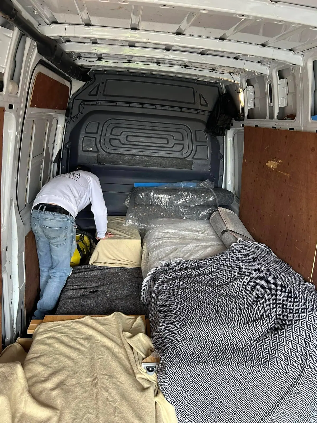 Optima Transport crew member carefully laying protective blankets over furniture in the van