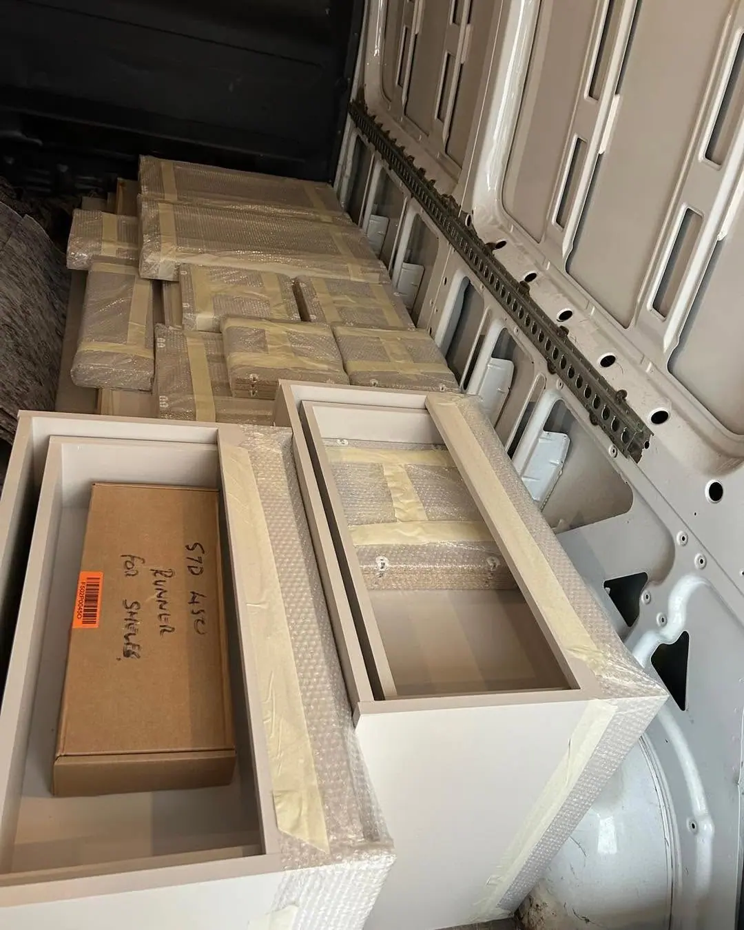Wrapped white cabinet and drawer units loaded in an Optima Transport van for a commercial removal