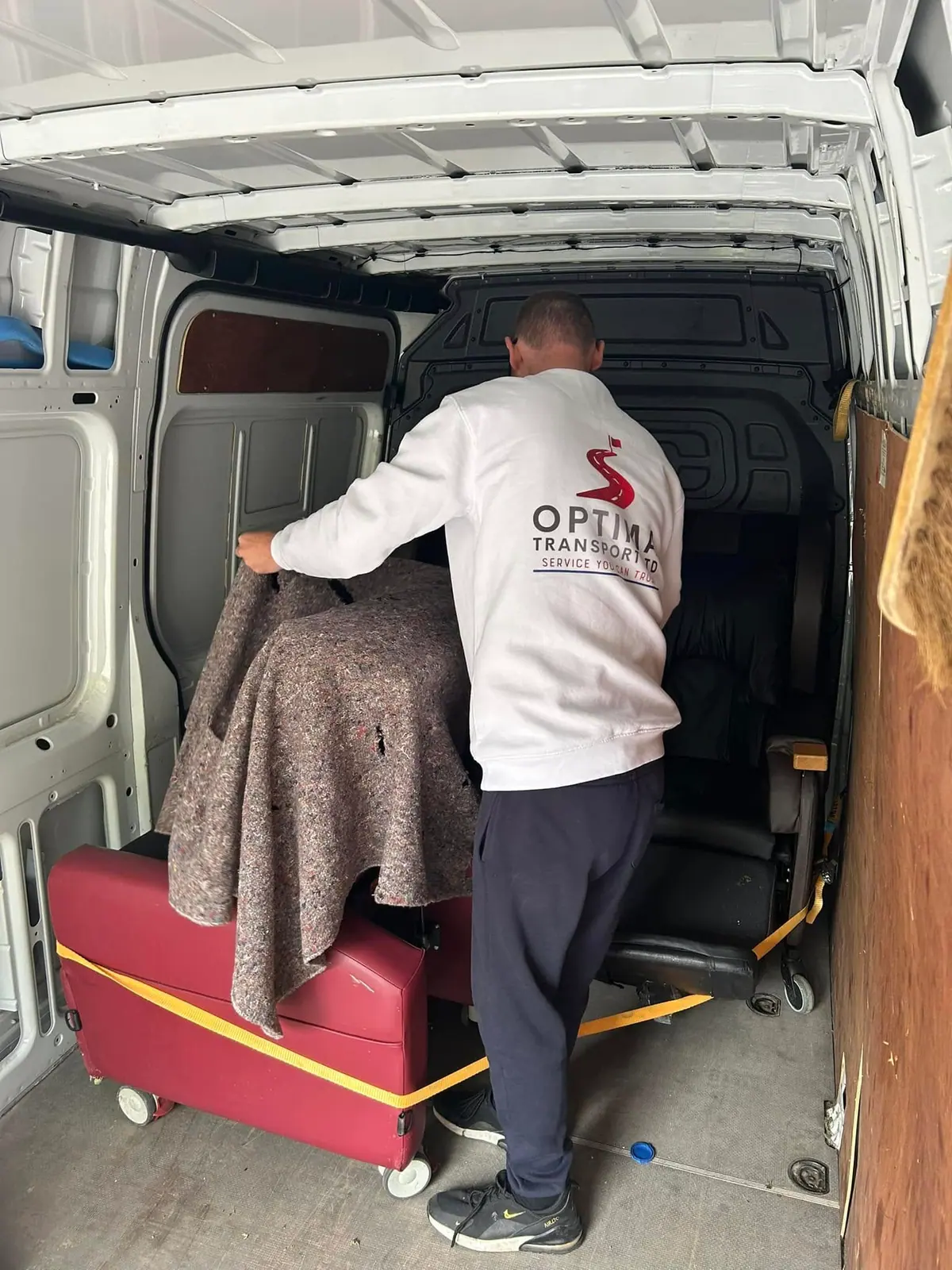 Optima Transport crew member lifting a blanket-protected item from a van during a domestic clearance