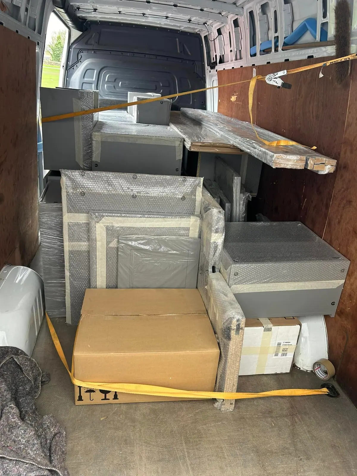 Wrapped equipment strapped securely inside an Optima Transport van during a factory clearance