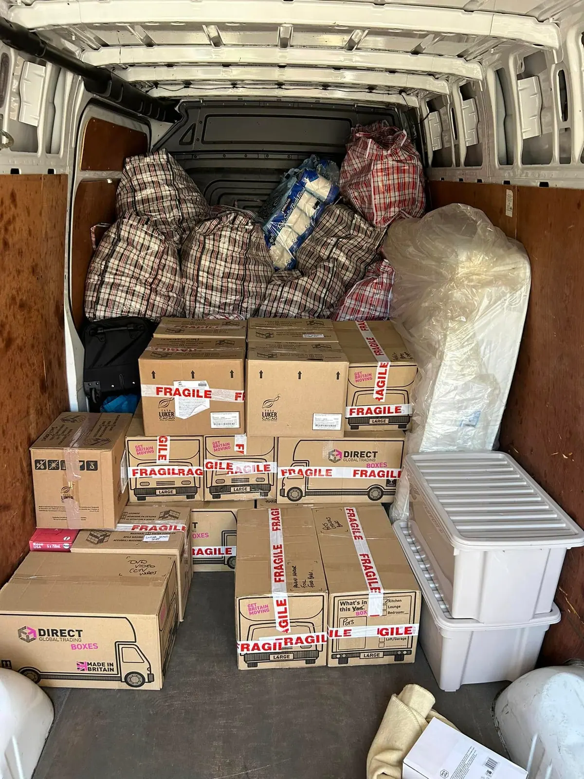 Neatly stacked fragile-labelled boxes packed securely in an Optima Transport van