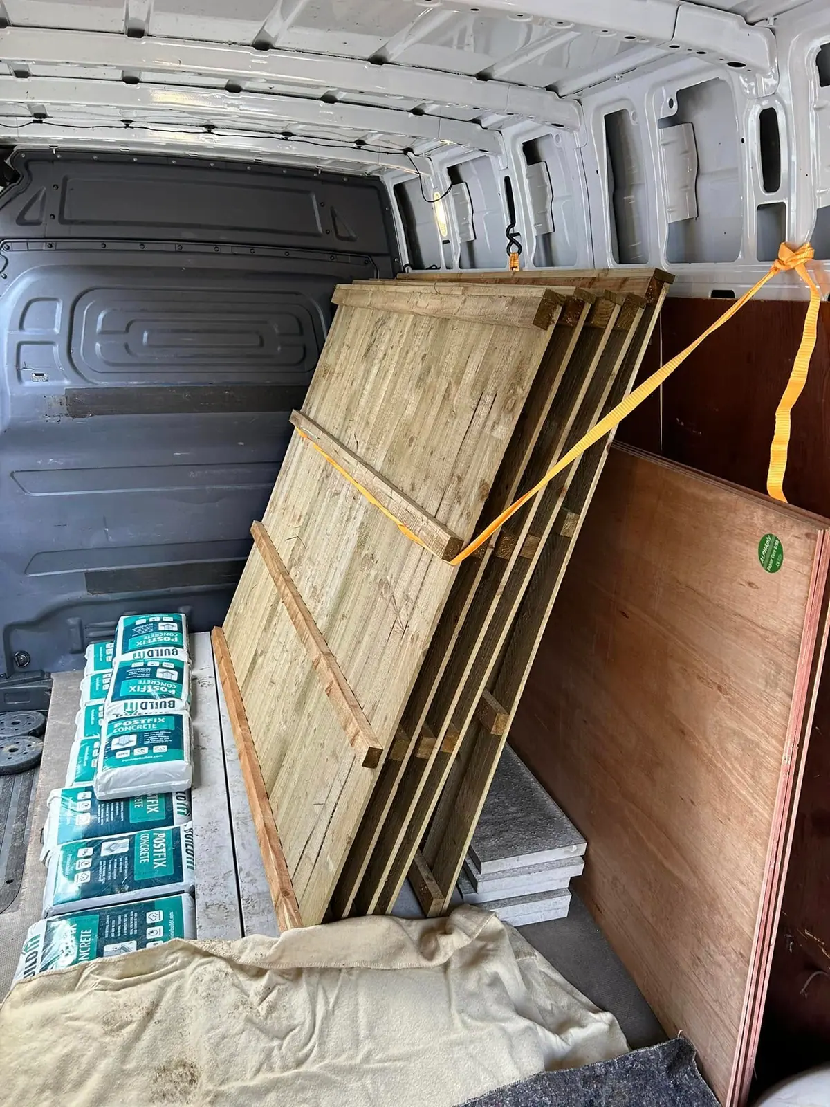Fence panels and bags of materials loaded into an Optima Transport van during a garage and outbuilding clearance