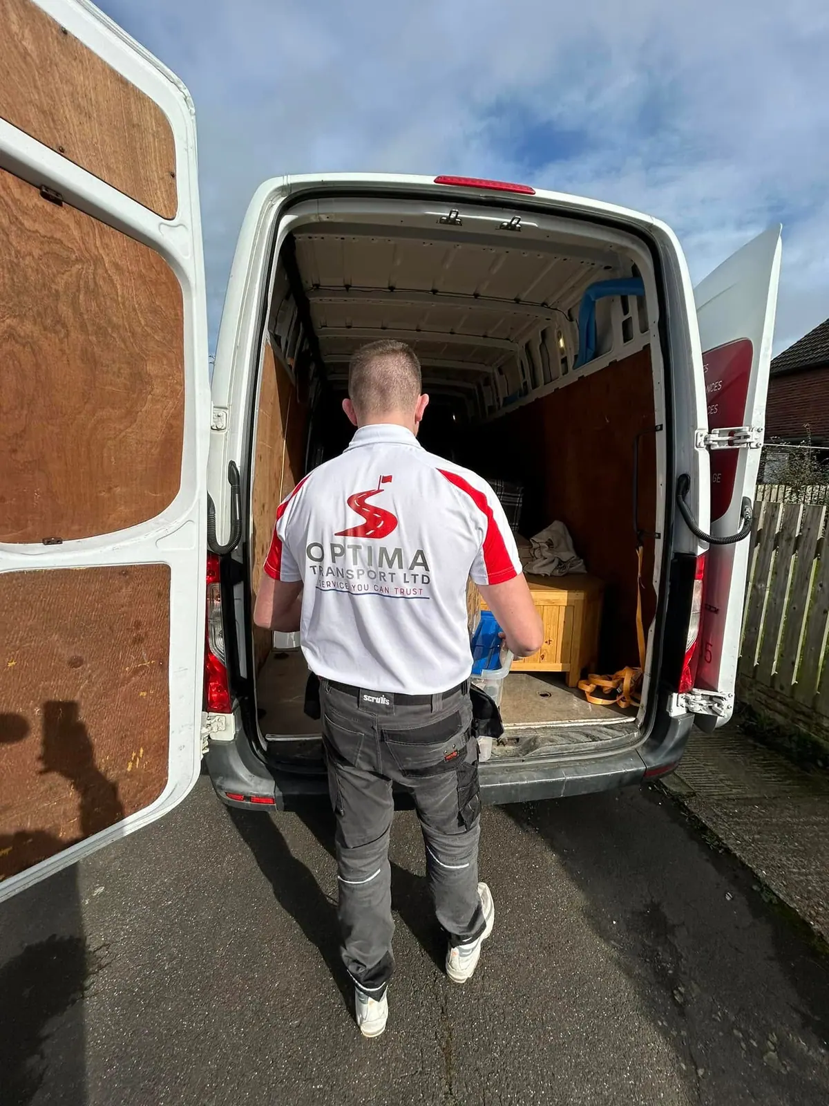 Optima Transport house removals crew member loading furniture into a van through the open rear doors