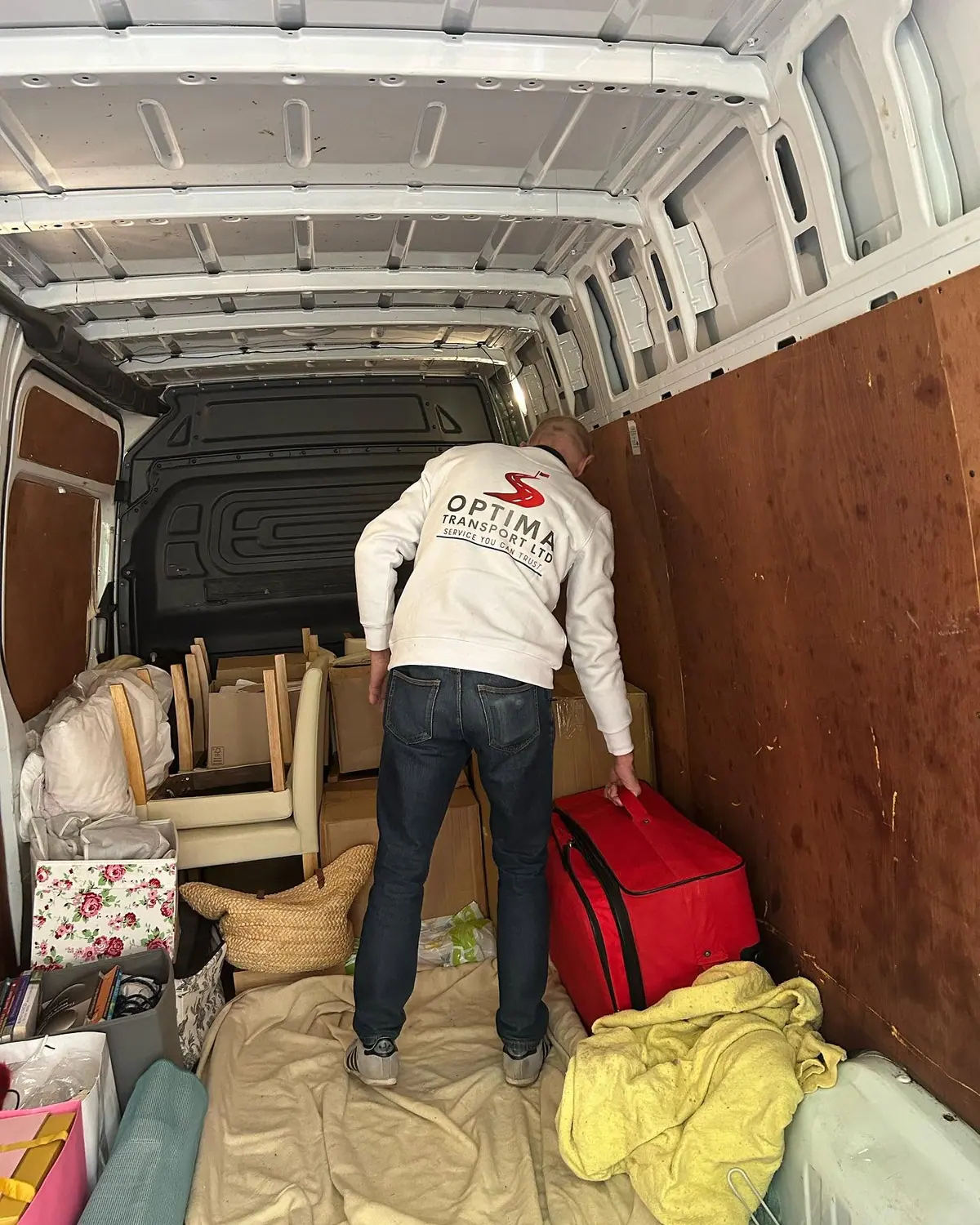 Optima Transport removals crew member loading household furniture and cushions into a van for a house move
