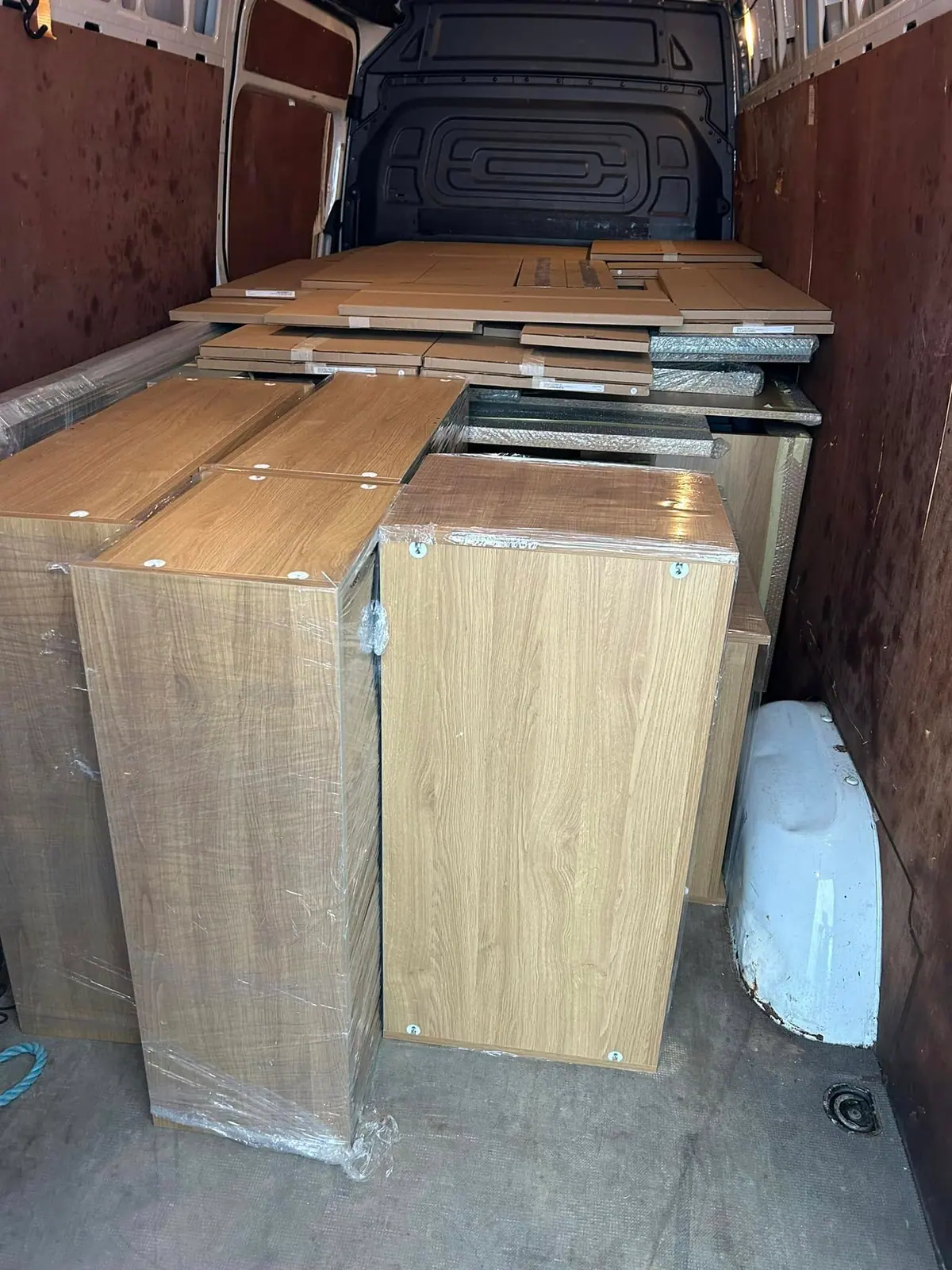 Shrink-wrapped oak furniture units loaded in an Optima Transport van for haulage