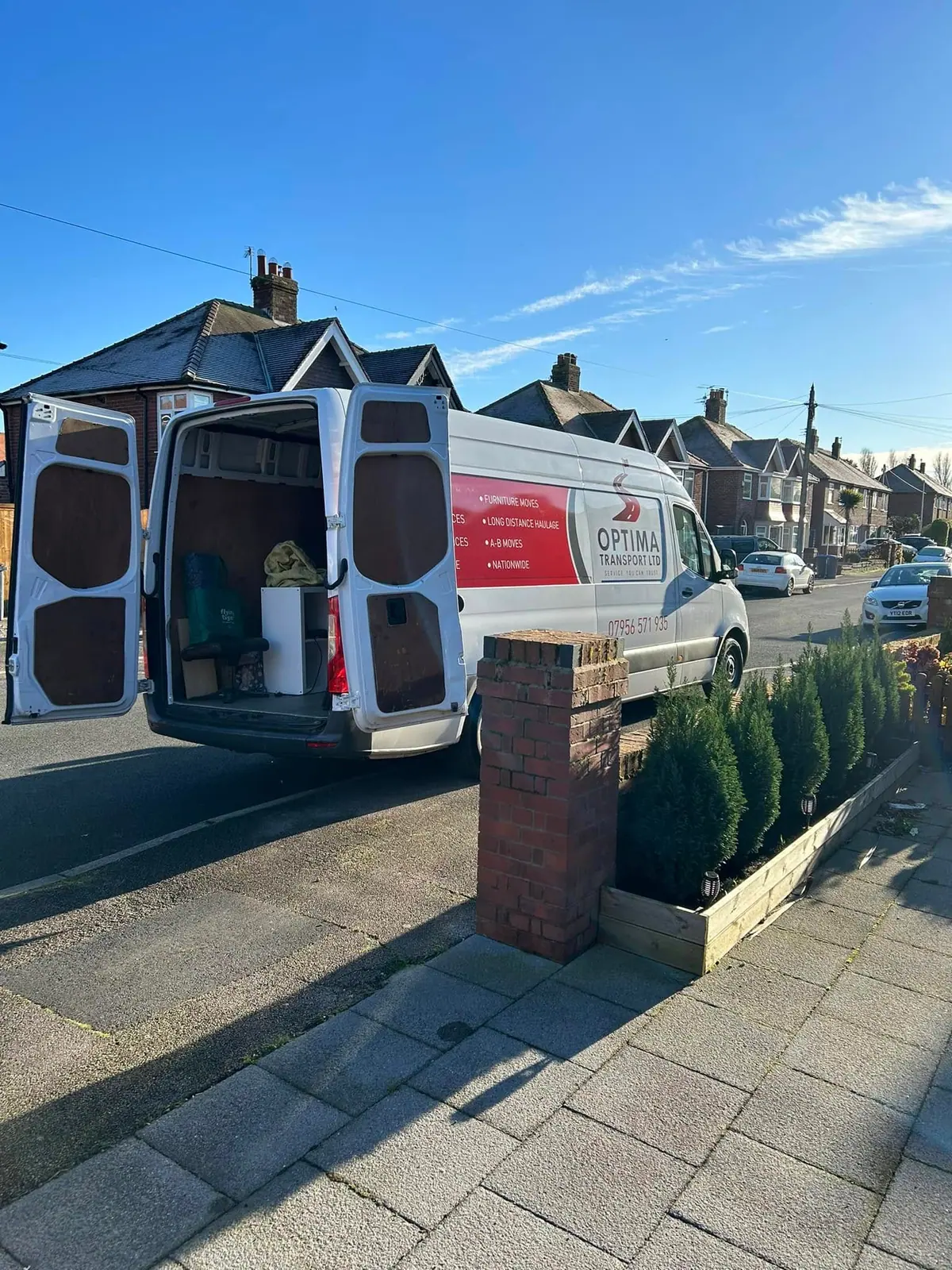 Optima Transport branded removals van with rear doors open on a residential street