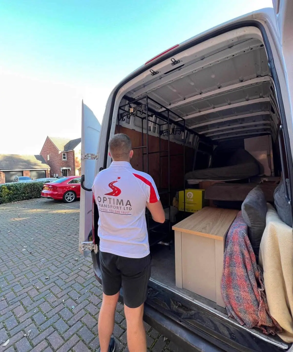Optima Transport crew member at the open rear doors of a removals van loaded with furniture