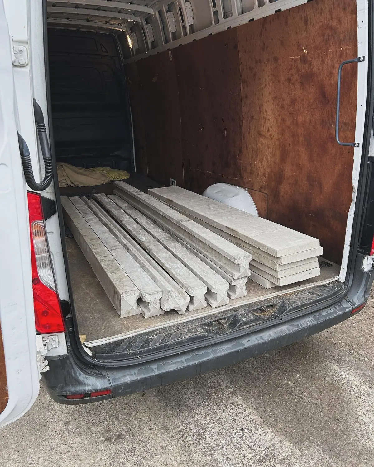 Concrete fence posts and gravel boards loaded in the back of an Optima Transport van for delivery