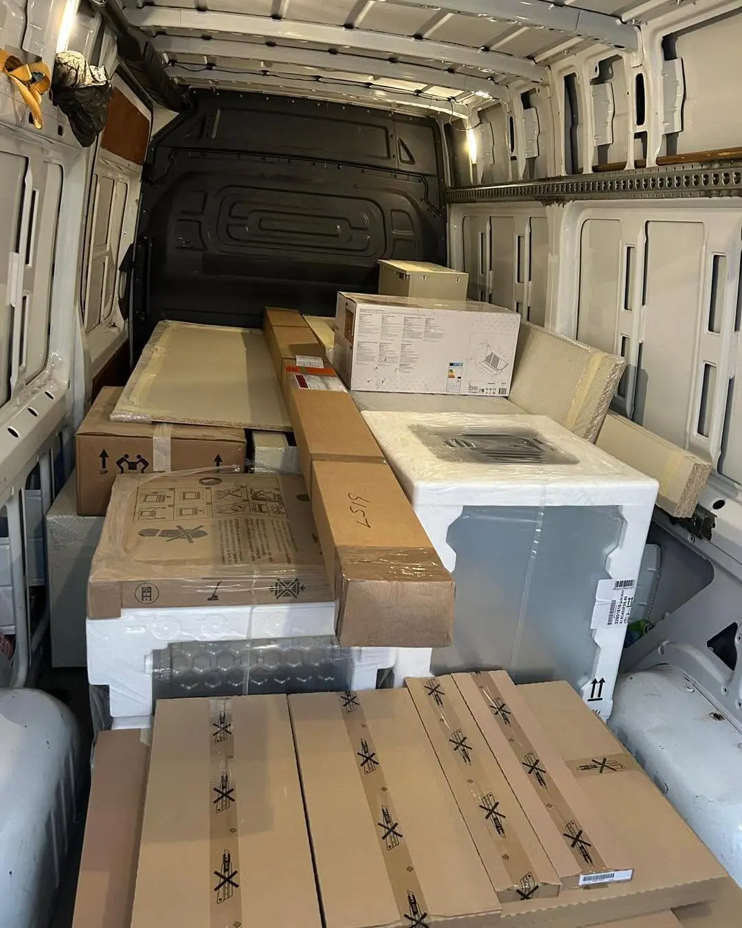 Appliances and boxes loaded into an Optima Transport van during a warehouse clearance
