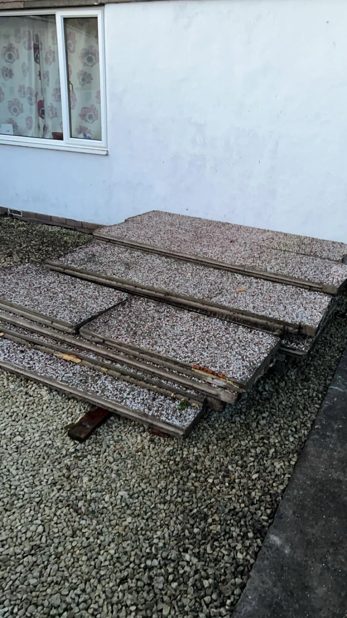 Old paving slabs and timber stacked outside a house ready for waste removal by Optima Transport